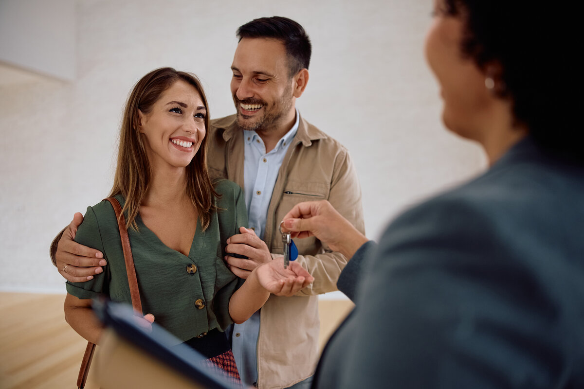 Schlüsselübergabe an ein Paar bei der Immobilienvermittlung