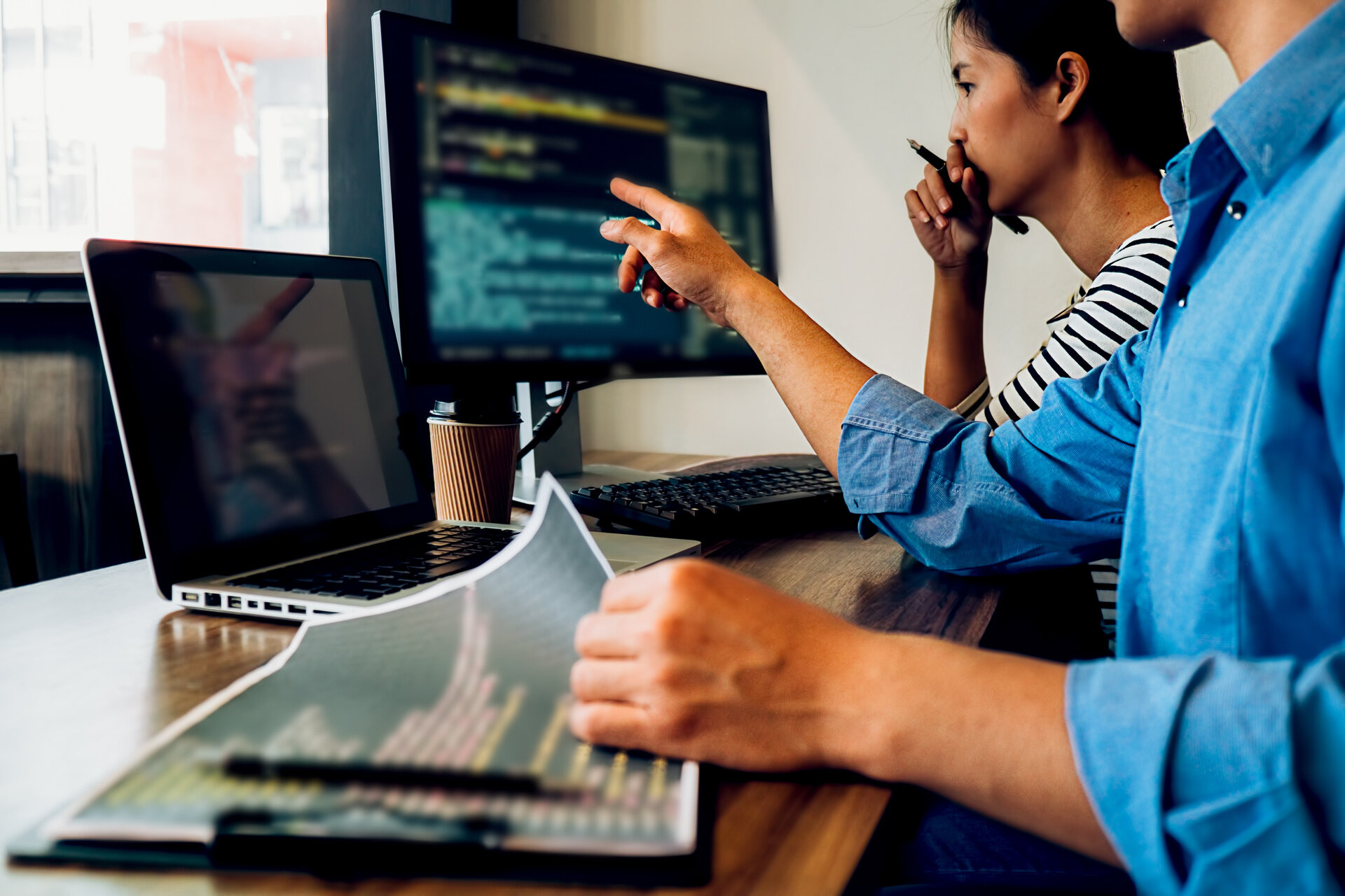Zwei Personen arbeiten gemeinsam an der Entwicklung einer Website am Computer