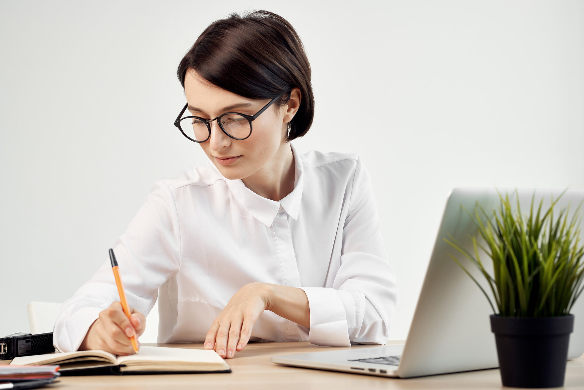 Weiterbildung Fachkraft für Bürowirtschaft (IHK) Frau arbeitet mit Laptop und Notizbuch an kaufmännischen Aufgaben