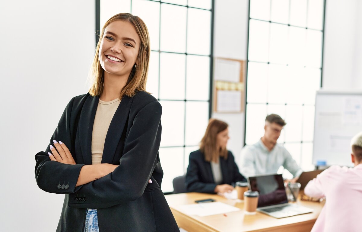 Weiterbildung Fachkraft Office-Manager*in (IHK) Office-Managerin steht vor einem Team in einem modernen Büro