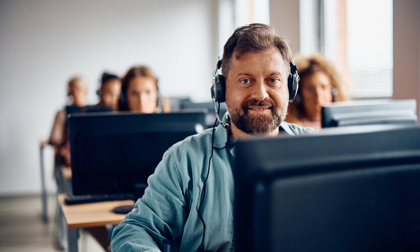 Gut vorbereitet in die Umschulung starten Umschüler mit Headset am Computer im virtuellen Präsenzunterricht