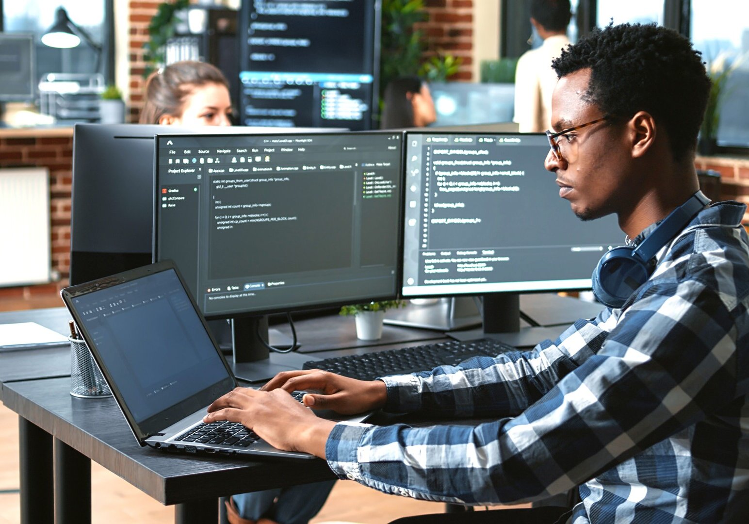 Fachinformatiker arbeitet an mehreren Bildschirmen und einem Laptop