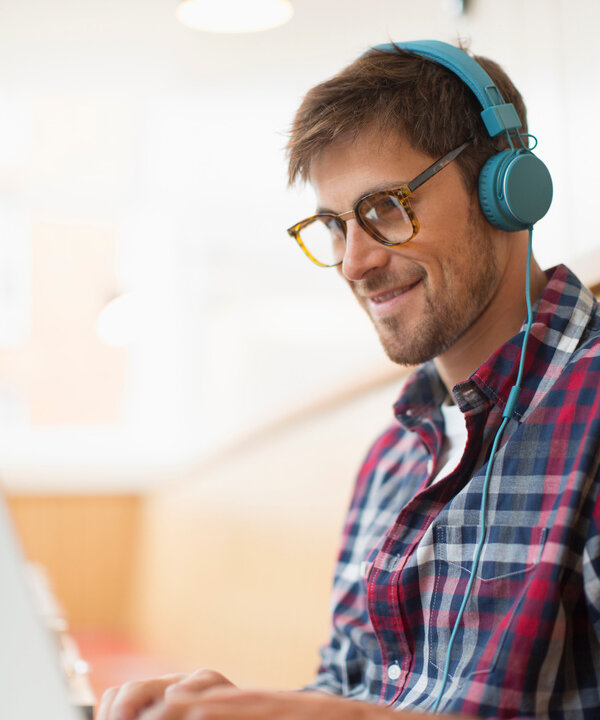 Teilnehmer lernt mit Kopfhörern am Laptop in einer Online-Weiterbildung für Sprache und Kommunikation