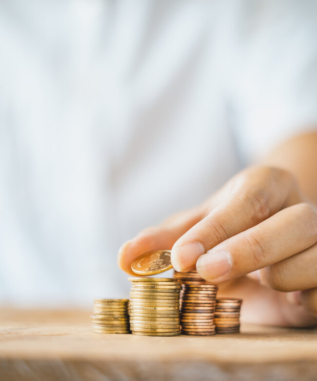 Hand stapelt Münzen – Symbol für finanzielle Förderung von Weiterbildung und Umschulung