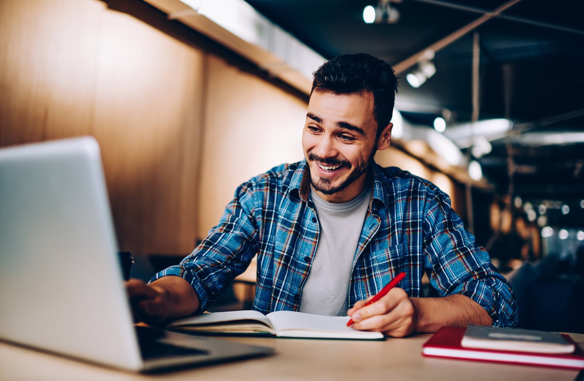 Mann lernt mit Laptop und Notizbuch an einem modernen Arbeitsplatz